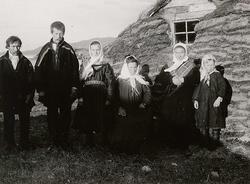 Familiegruppe (6) i samisk drakt, oppstilt foran gamme, Laks