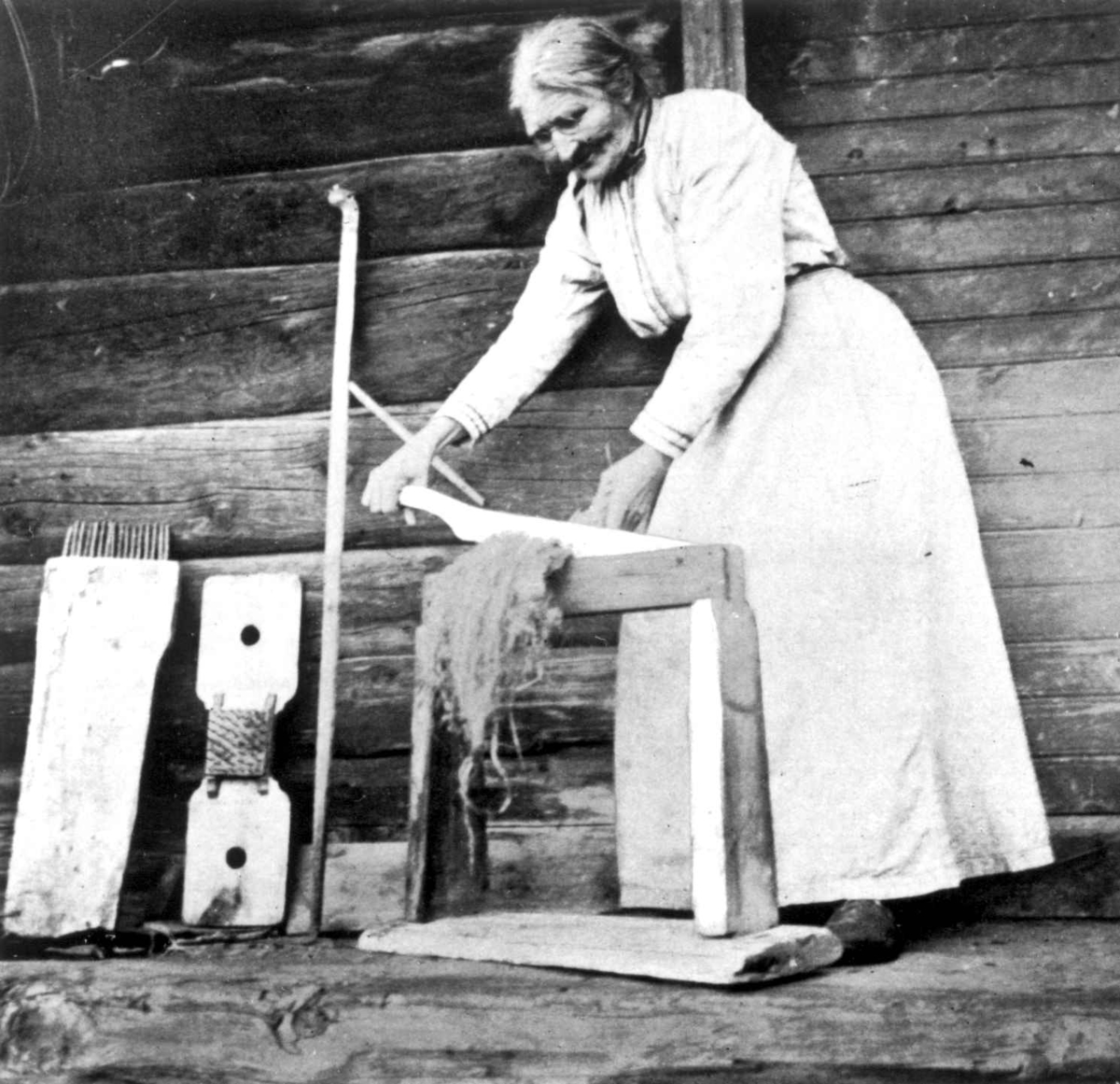 Bråking. En kvinne brekker lin på en linbråke. Meldal, Nord-Trøndelag.