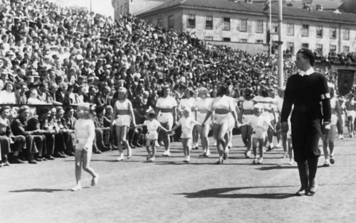 Fra Oslo under fredsdagene i 1945. Idrettens Dag på Bislett Stadion 3.juni. Idrettskvinner og barn marsjerer på den oppmerkede banen.