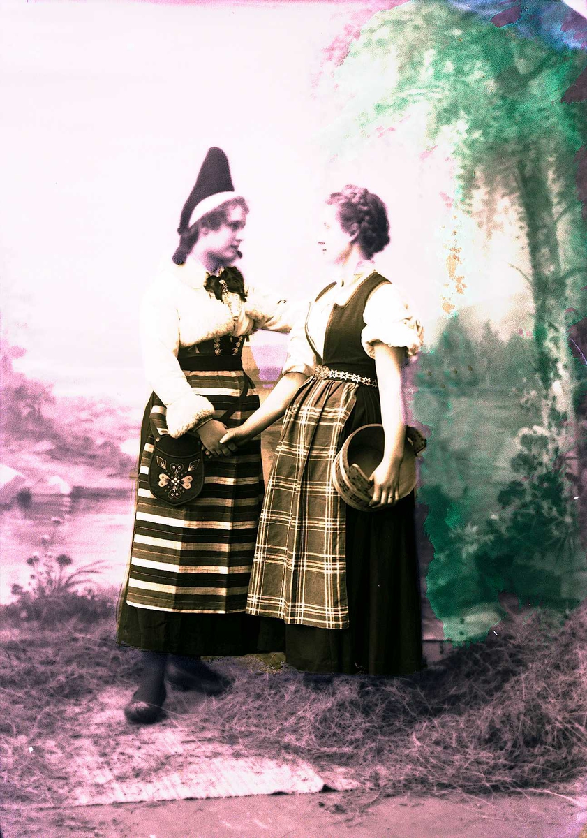To kvinner i drakt tar hverandre i hånden. En holder en ambar under armen. Malt bakgrunn med landskap, høy på gulvet foran teppet.