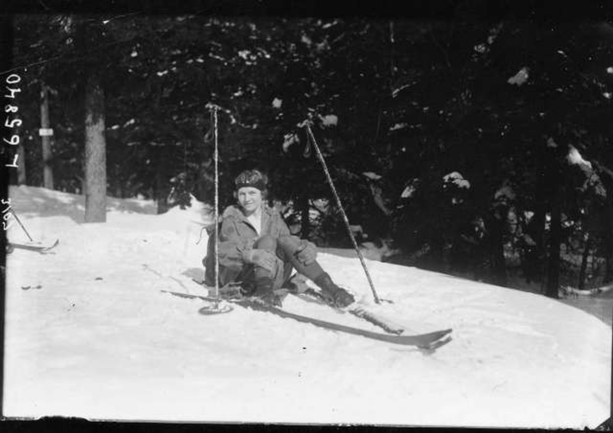 Kvinnelig skiløper har pause, sitter i snøen.