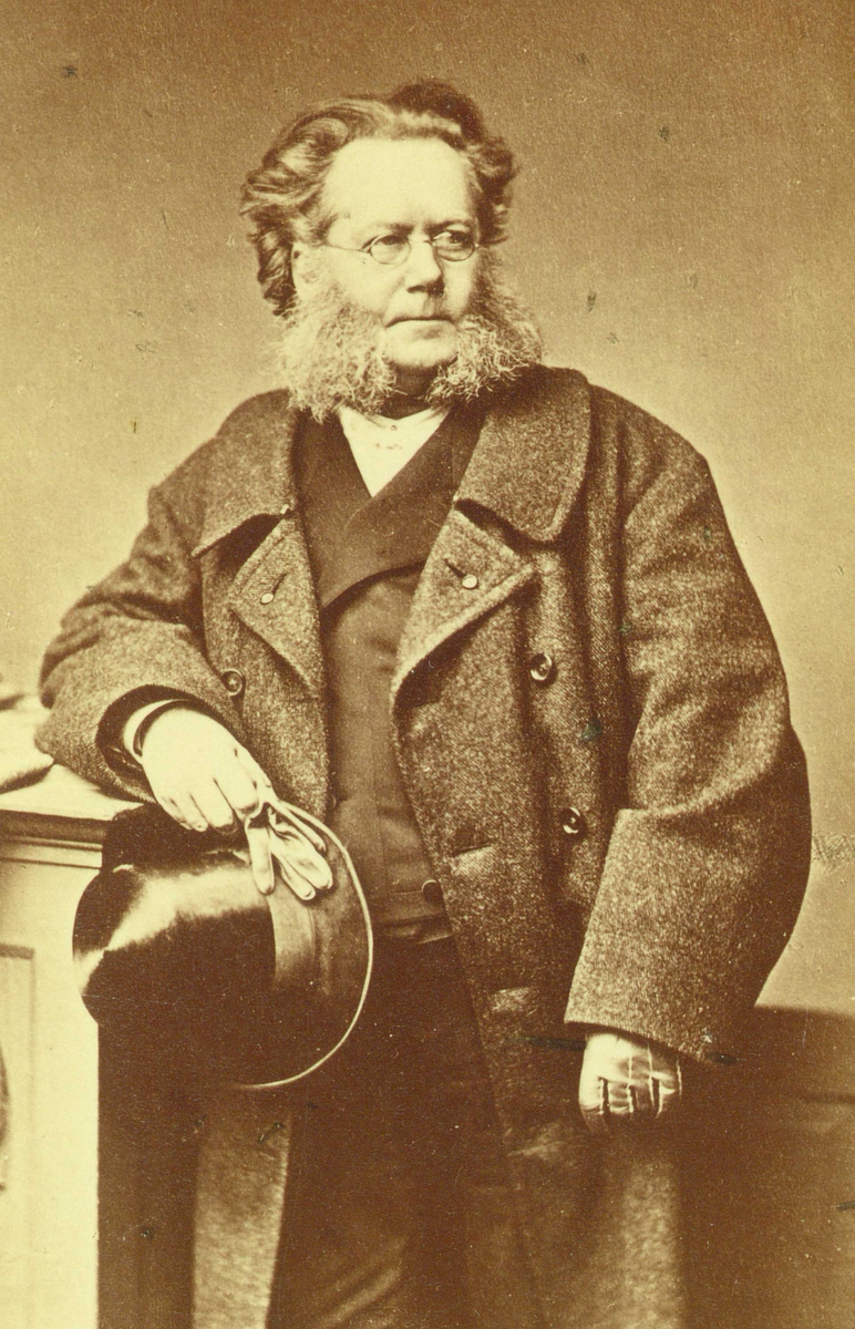 Portrett av Henrik Ibsen stående mens han holder flosshatt og hansker i hånden.
Bildet er tatt i Mûnchen i 1878 av Franz Hafnstaengel.