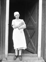 Juni 1925. Ragna, antakelig hushjelp, står med en katt på ar