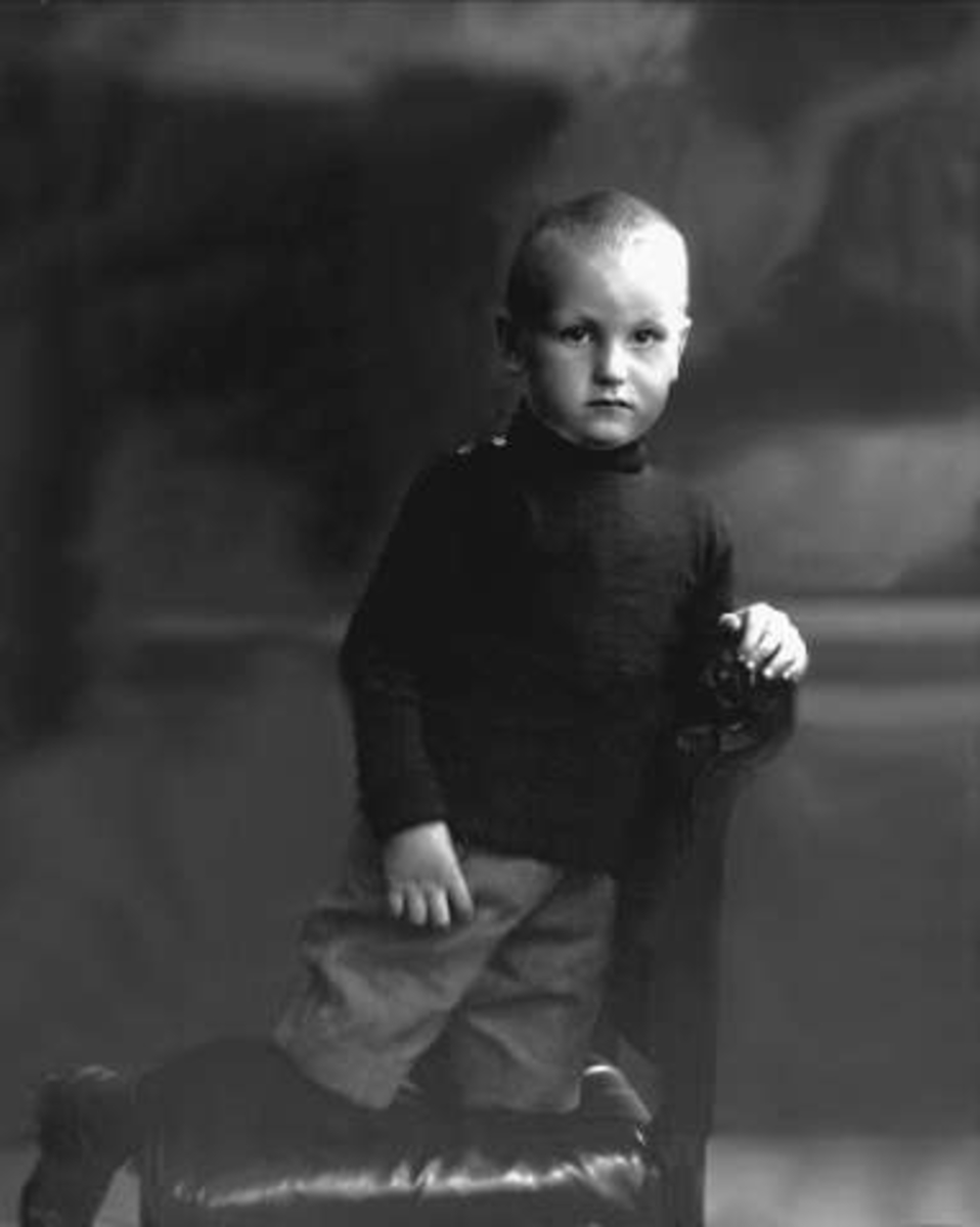 Portrett, gutt i mørk genser, kortbukser, strømper og sko. Kaptein Grinakers sønn.