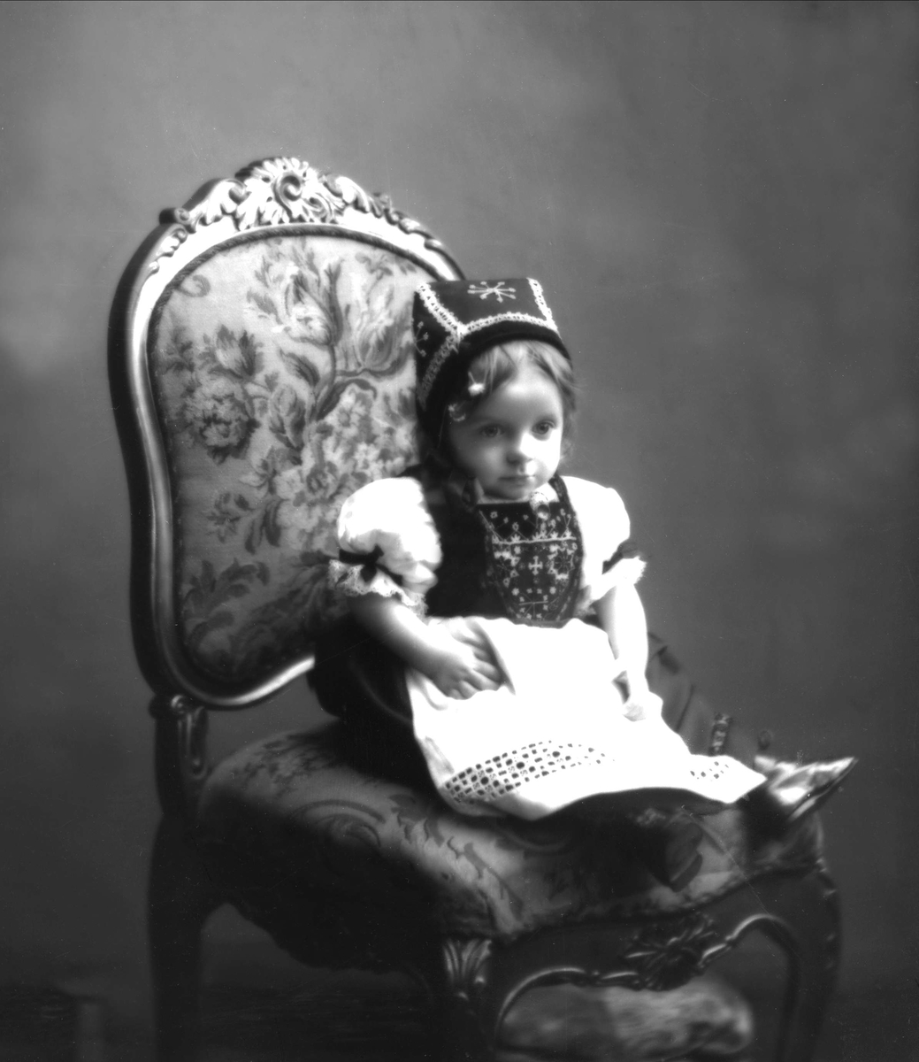 Portrett, liten pike på stol, i hardangerbunad. Fuglesangs datter.