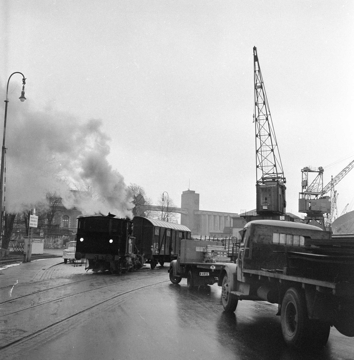 Festningskaia med havnebanen med siloen på Vippetangen i bakgrunnen.
Jernbanen med kryssende trafikk fotografert i 1956.