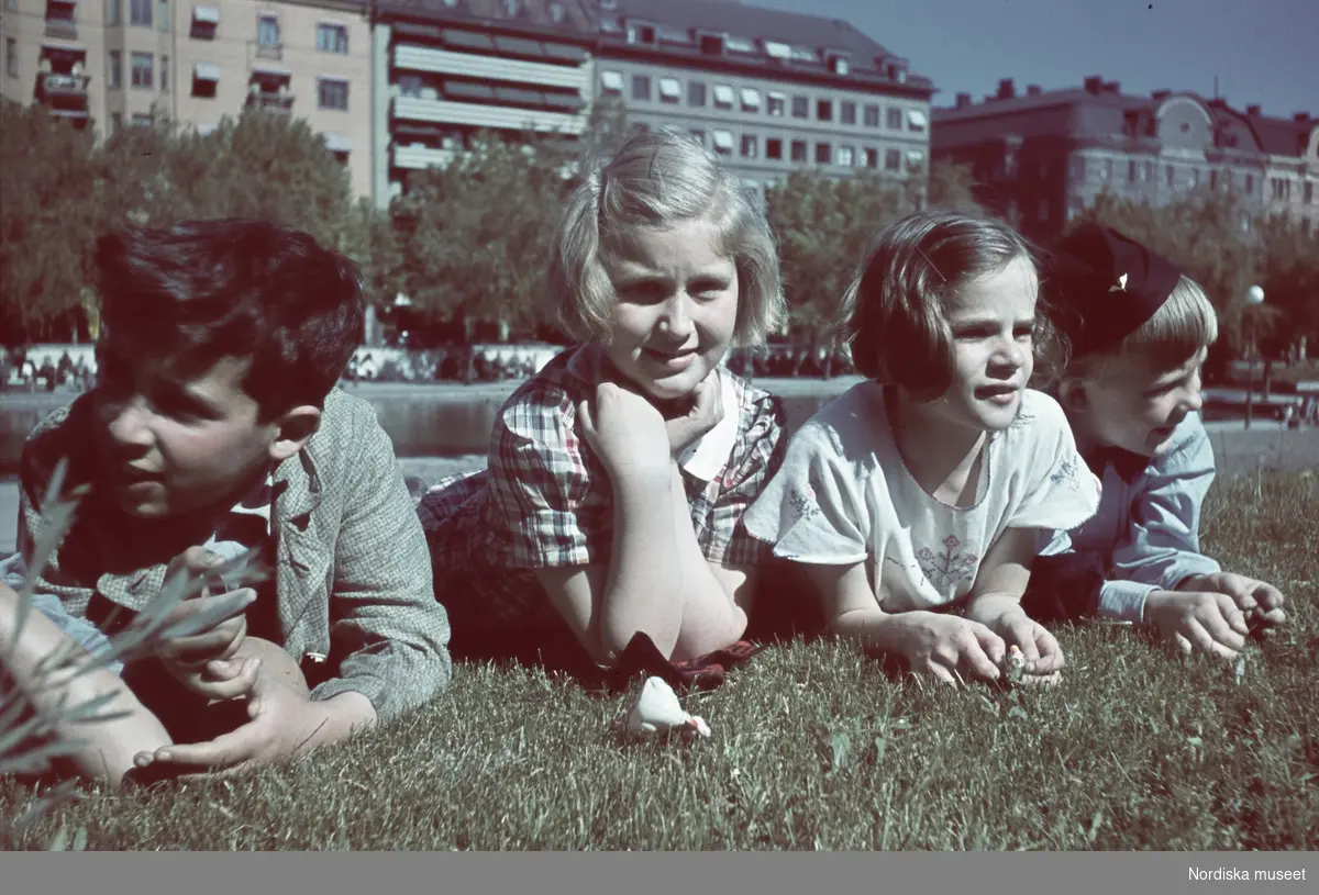Fyra barn ligger på mage på gräsmatta.
