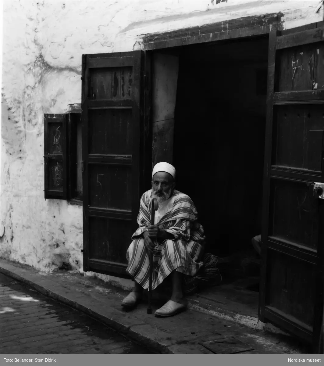 Man med käpp sitter i en port på gatan i Tétouan, Marocko