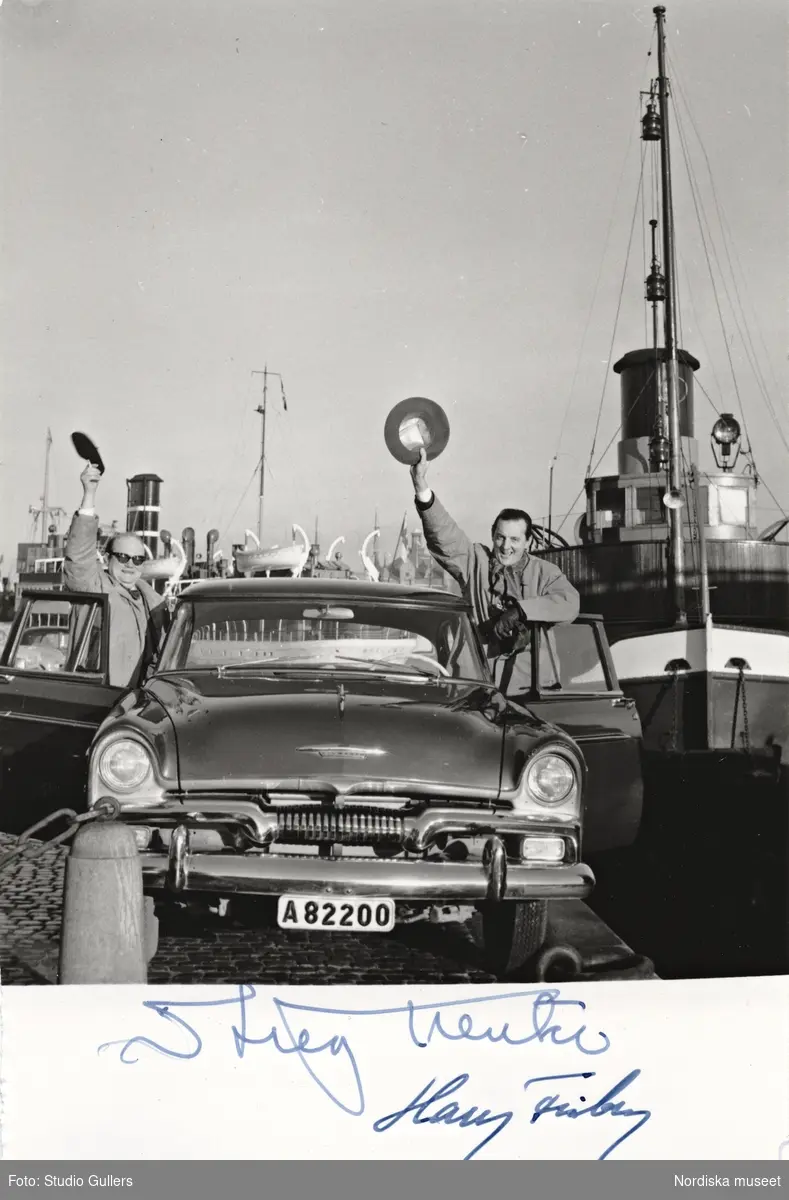 Stieg Trenter och KW Gullers ("Harry Friberg") vid en bil, fartyg i bakgrunden. Signerat fotografi.