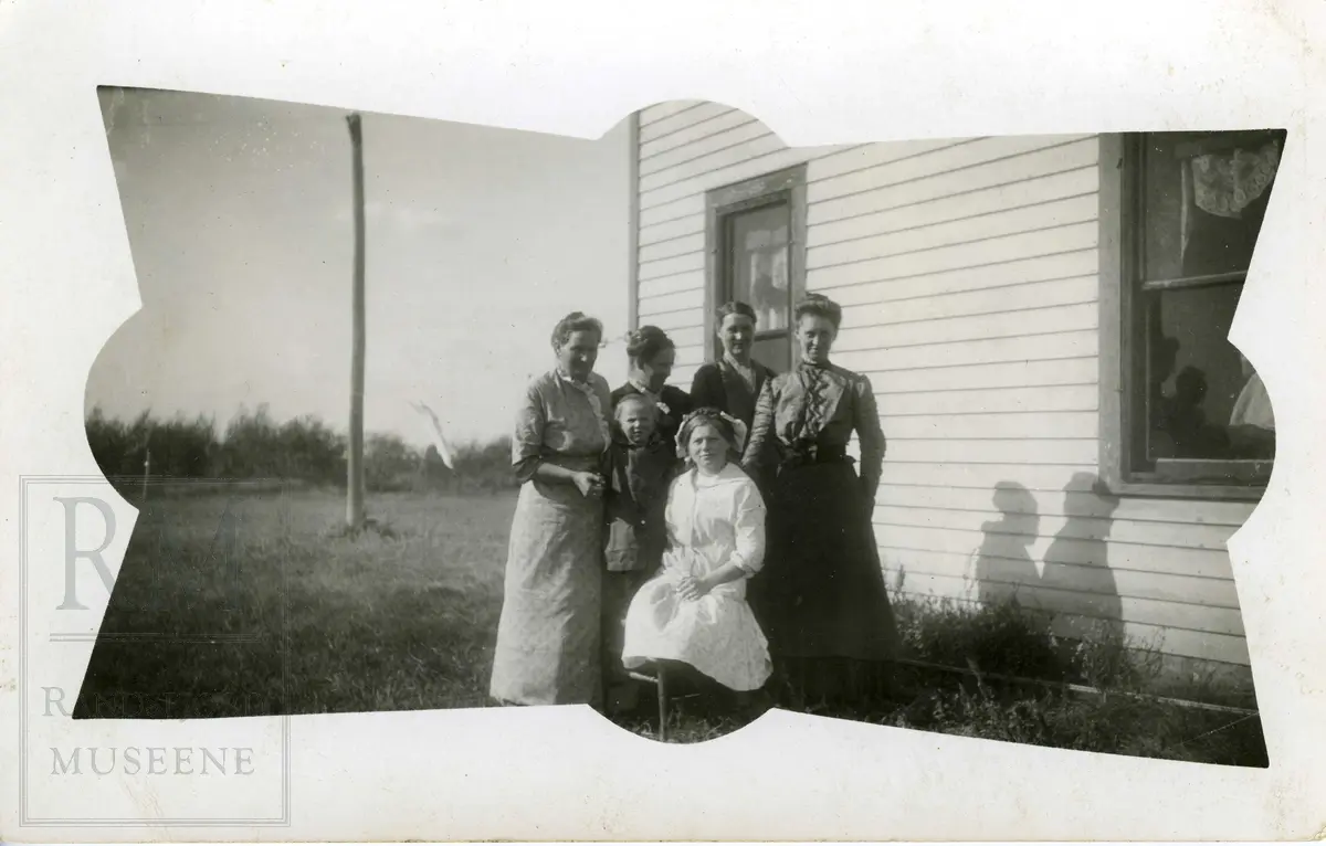Gruppe med fire kvinner og to barn ved et bolighus