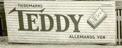 Reklame for Tiedemanns Teddy sigaretter på plankegjerde i Br