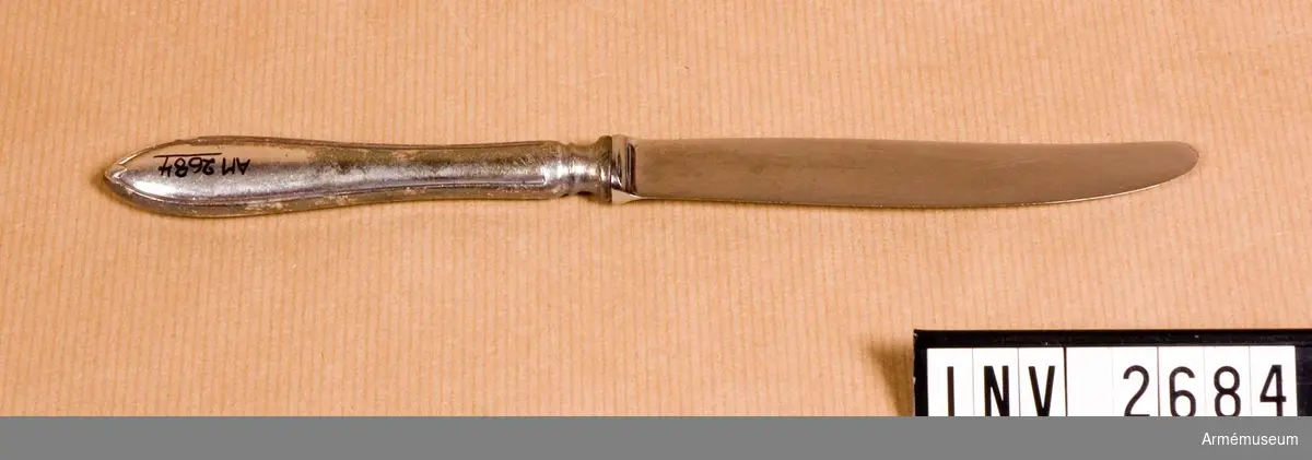 Av nysilver. Skaft av nysilver. Knivbladet av rostfri stål "MADE IN SWEDEN", märkt "GENSE" och "O.M." (=officersmäss). 