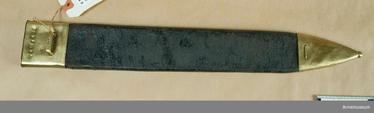 Balja av svart läder med ca 60 mm högt munbleck och 95 mm hög doppsko av mässing, på det förra  en horisontal, platt mässingsbygel för uppkoppling.
