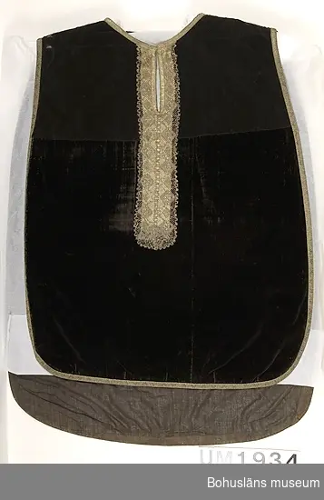 Mässhake från Uddevalla kyrka i svart bomullssammet kantad med band av förgylld metalltråd; krucifix i silverplåt eller försilvrad (förgylld?) plåt på ryggsidan. Fodrad med ett mörkt brunt glättat linnetyg. 
Mässhaken är troligen tillverkad på 1740-talet.
Krucifixet har lossnat och förvaras separat. 
Pålött på krucifixet "INRI" och "O.S.S.:M.J.D. ANNO.1745." Krucifixets mått 51,0 x 29,7 cm.
Påsydda metallbokstäver under krucifixets plats: "O.S.S : M.J.D"
På framsidan en liksidig spets knypplad av metalltråd och silke-/linnetråd; monterad längs halsöppningen och en bit ner. Längd 60 cm.
Delar av sammetstyget så sliten att det lagats/bytts ut mot en brunsvart sammet med mattare karaktär.

Enligt Marie-Louise Franzén, Statens Historiska museum, Stockholm i december 2002: Mässhakar av denna typ är ovanliga i Sverige. Det finns mycket få bevarade. I Historiska museets samlingar finns inte någon enda mässhake från Bohuslän.

Ur handskrivna katalogen 1957-1958:
Mässhake, U-a kyrka
H. 106 resp. 123 cm.
svart sammet, silverstickn. krusifix i försilvr. plåt; mont. som föreg.(UM1933). 
ramen: 139,5 x 106 cm. O.S.S.:M.J.D. år 1745.

Lappkatalog: 12
