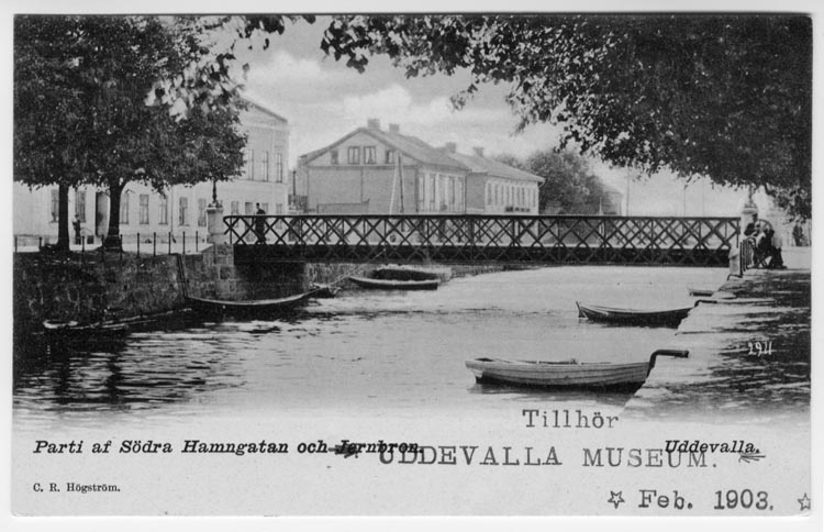 Tryckt text på vykortets framsida: "Parti af Södra Hamngatan och Järnbron Uddevalla."