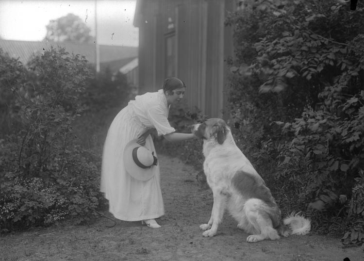 Kvinna med hund i trädgård
