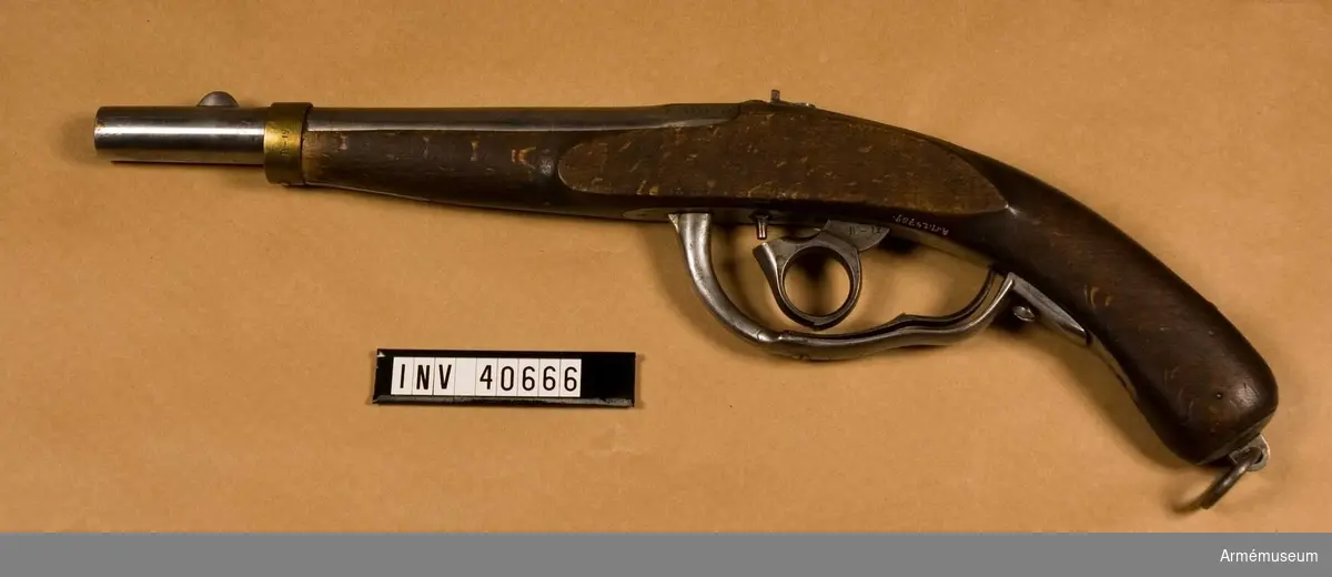 Grupp E III.
Med slaglås.
Pistolen har järnbeslag förutom näsbandet som är av mässing. Den har underliggande slaglås, där hanen har ringformat tumgrepp. På kammarstycket står dels en oläslig stämpel i form av monogram, M -1841, B- 1842-12, vilket kan betyda modell: 1841, tillv. 1842, tillverkningsnummer 12. Det senare numret förekommer på pistolens samtliga delar.