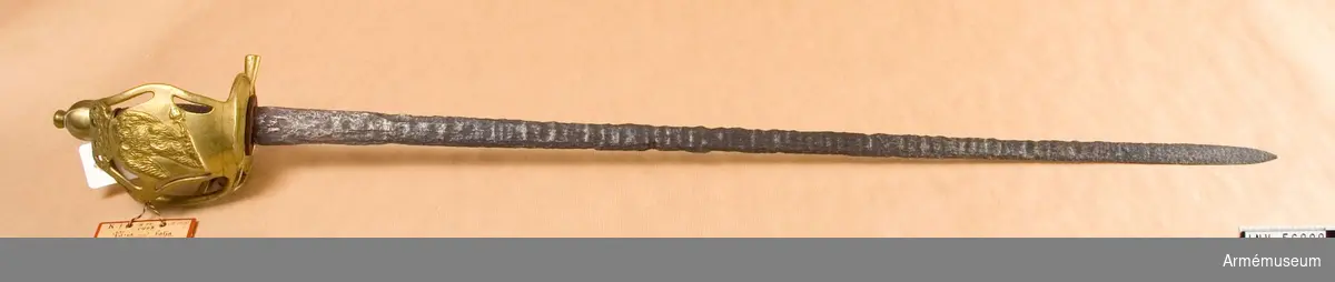 Grupp D II.
1733-1797.
Klinga och kavel i original. Klingan är starkt deformerad av rost. Kaveln är skadad. På den inre parerplåtens undersida finns "No: 462".