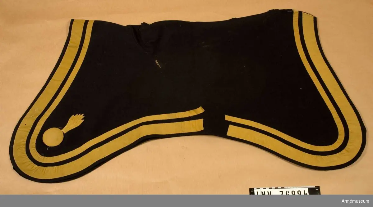 Grupp: K I.
Regemente: Artilleriet. 
Tillverkad av: mörkblått kläde med en smal och en bredare list av gult kläde.
