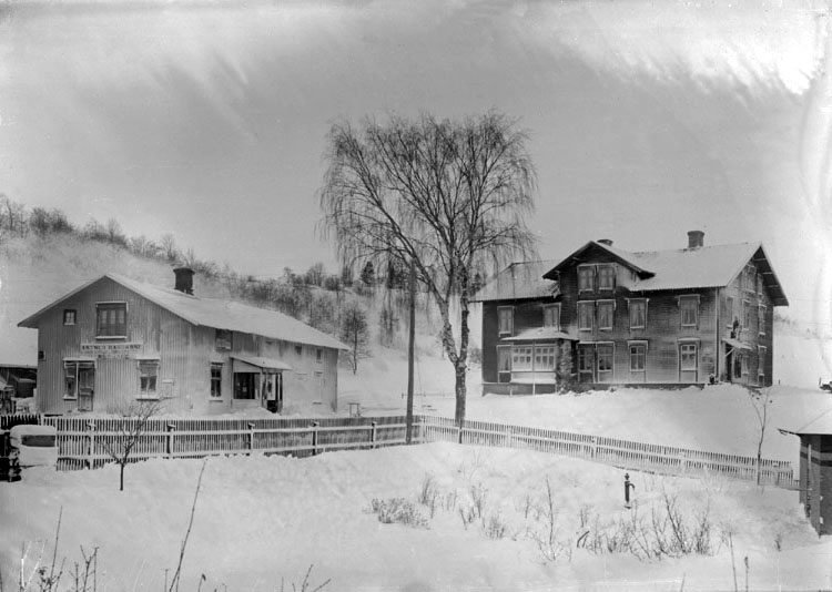 Enligt senare noteringar: "Till vänster Arthur Hanssons affär vid järnvägsstationen, byggd 1904 då rörelsen flyttat från Håby (etablerat 1889). 
Huset till höger byggt 1906 av A. Hansson som bostad. Inrymde postkontor (som flyttade från Kviström) till 1933, då nytt posthus byggdes intill. Det inrymde också kommunalkontor, från början av 1940-talet fram till 1960." (BJ)
