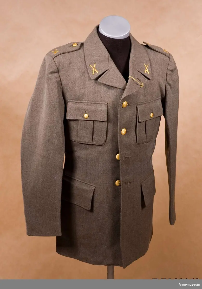 Stl 96 II .Av samma snitt som uniform m/1939. Daglig dräkt av gråbrungrönt  tyg. Bärs till mörkt gråbrungröna byxor. Tjänstetecken  mattförgyllda.