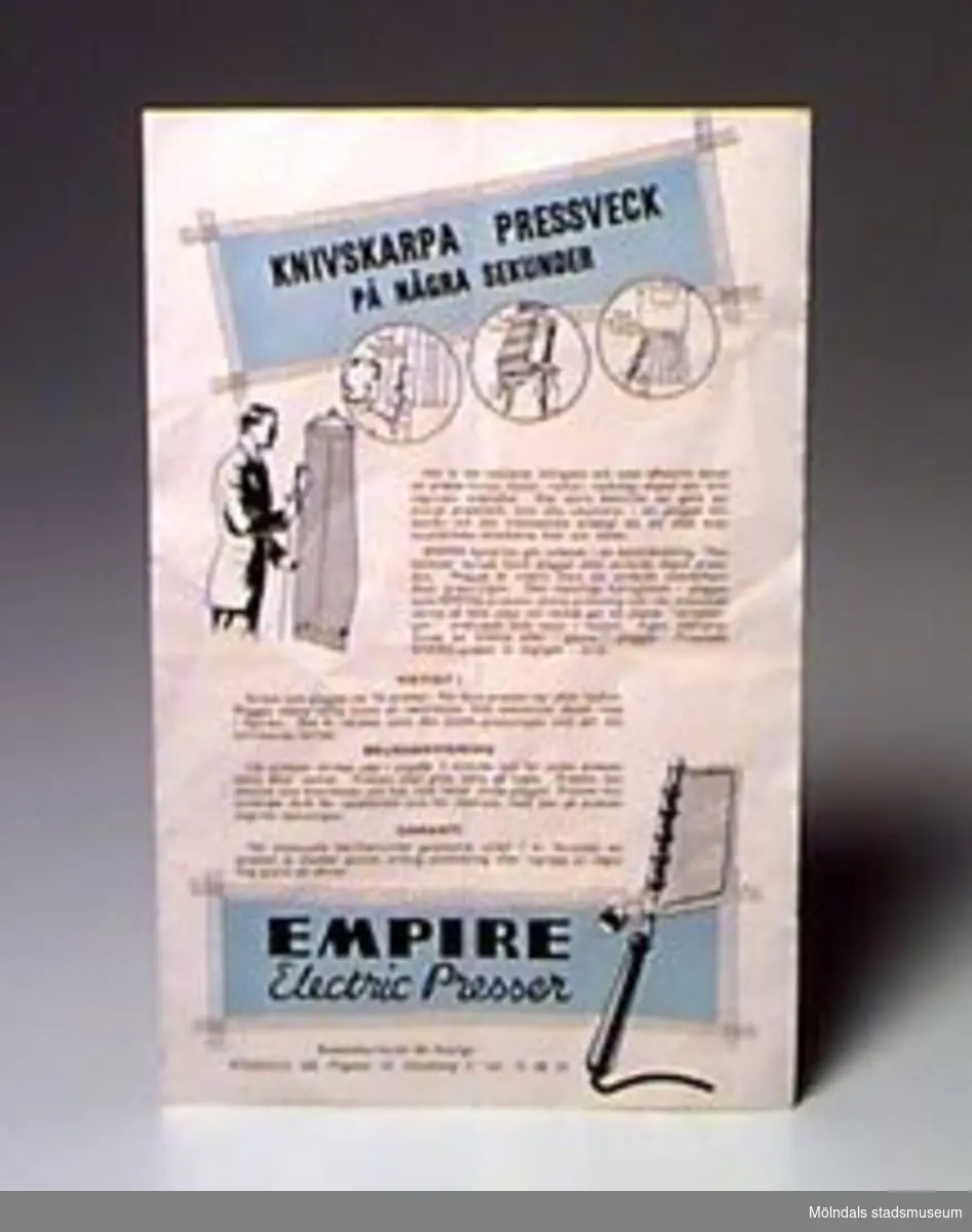 Elektrisk byxpressare. Två plåtar sitter på en stång och bildar en klämma. Stången sitter fast i ett trähandtag med elektrisk sladd. Tillhörande bruksanvisning. Märkt: Empire Electric trouser presser British made 120 -130 volts. AC/DC.Ägaren/givaren inköpte apparaten i "Lopplådan" i Krokslätt 1987.