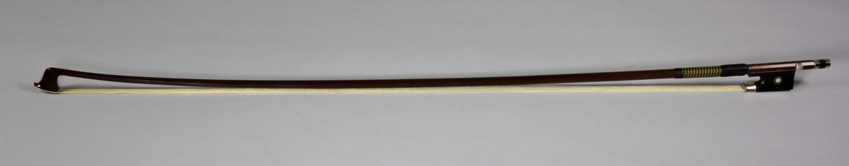 Stråke, fiolstråke, tillverkad av rödbrunt trä med ljust tagel. Vanlig modell med frosch och skruvspänning.