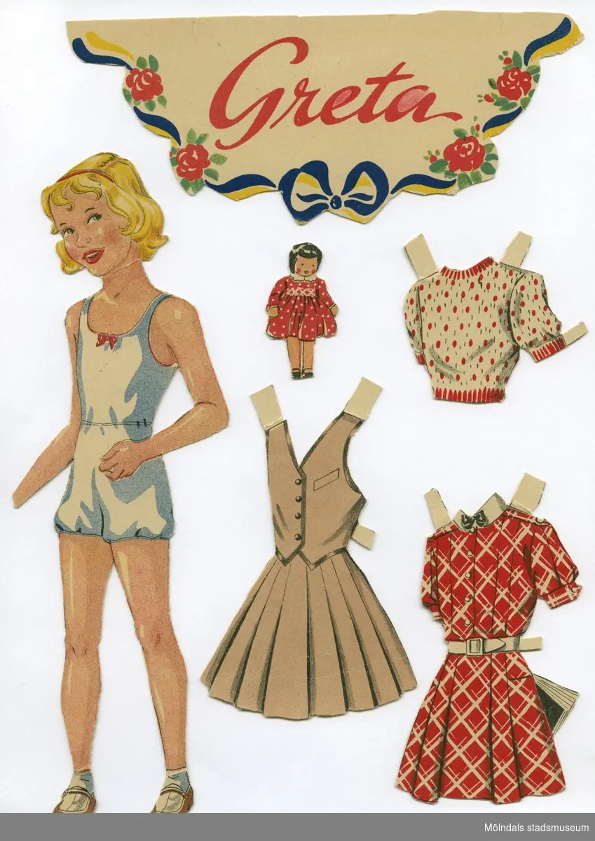 Pappdocka med kläder och tillbehör från 1950-talet. Docka och kläder är märkta "Greta" på baksidan - dockans namn. Dockan föreställer en flicka med blont hår och rött hårband, iklädd underkläder, strumpor och skor. Garderoben består av sex klänningar, två blusar, två kappor, en morgonrock samt fem huvudbonader. Hon har även tillbehör, såsom väskor och en docka. Det finns också ett urklipp med dockans namn, inramat av rosor och blågula band. Docka och kläder förvaras i ett brunt kuvert, märkt "Greta" men som ursprungligen är en försändelse från Göteborgs Arbetarekommun, Folket hus, Göteborg. 