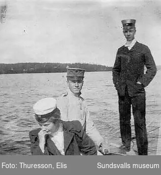 Två män, varav en i militäruniform, och en kvinna i båt.
