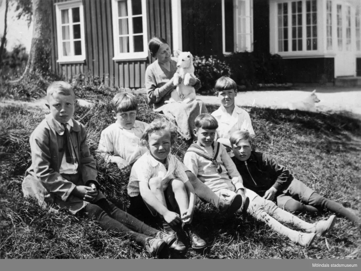 Valdeborg Johansson med hund i famnen tillsammans med sina elever utanför skolan, våren 1934. Text på fotots baksida: "Småfolk". Samma elever som på bild 1992_0007, 0008. 
Ur Valdeborg Johanssons fotoalbum.