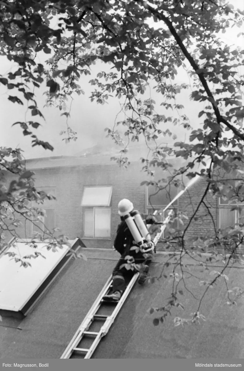 Soab-branden i Stora Götafors den 4 juni 1986. En brandman sprutar vatten från taket på andra sidan gatan.