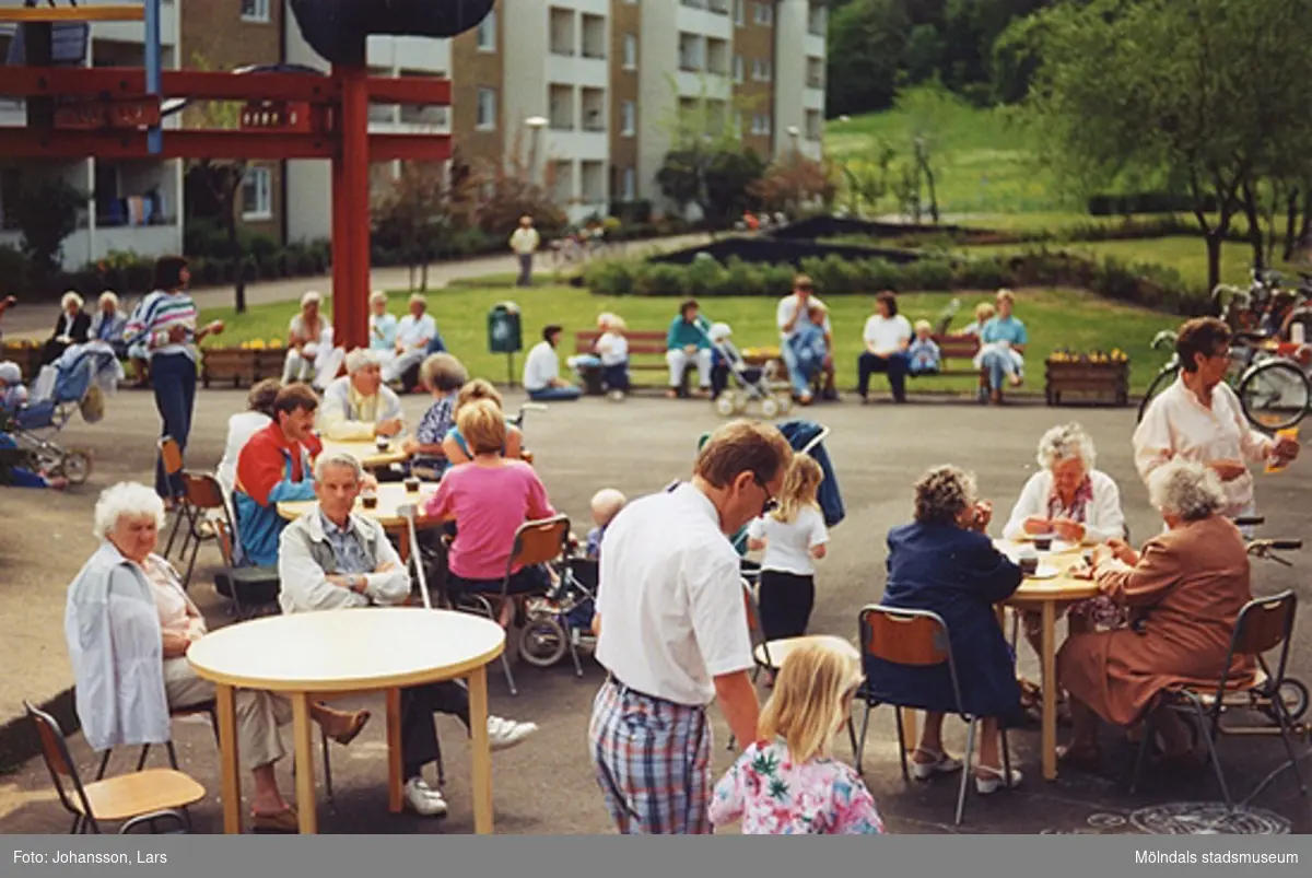 En av bostadsrättsföreningen Tegens gårdsfester i Kvarteret Rullharven 1989. Man hade bland annat korvservering, poängpromenad, spel, tävlingar, sång- och musikunderhållning m.m. Vid bordet längst fram till vänster sitter Nils Rossing med fru. I förgrunden går Jan Wallström med dotter.