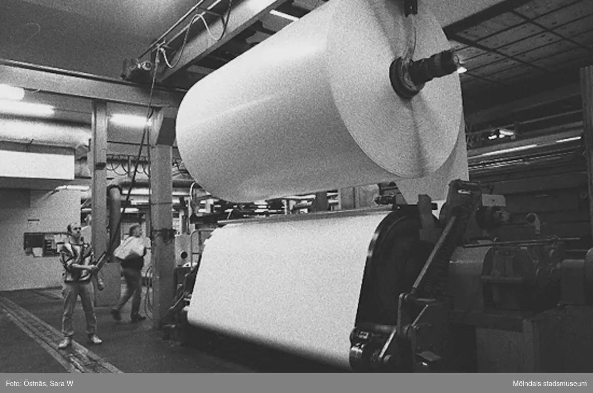 Män i arbete med en pappersbal, 1980-tal.
Bilden ingår i serie från produktion och interiör på pappersindustrin Papyrus.
