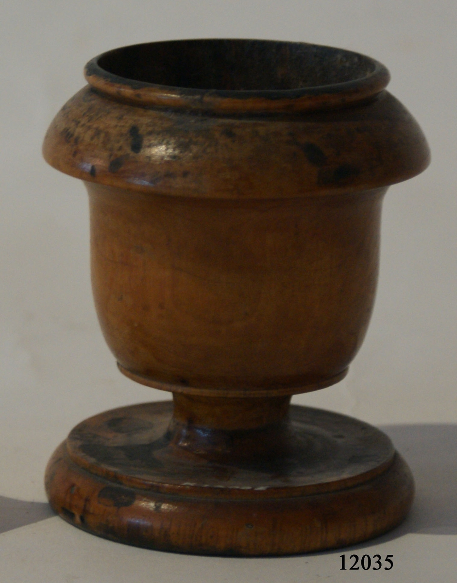 Pennställ, svarvat i furuträ i form av en urna med foten bredare än själva urnan. Avsedd för förvaring av hagel, vari pennan ställdes.