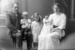 Studioportrett av et par med tre barn - den minste i dåpskjo