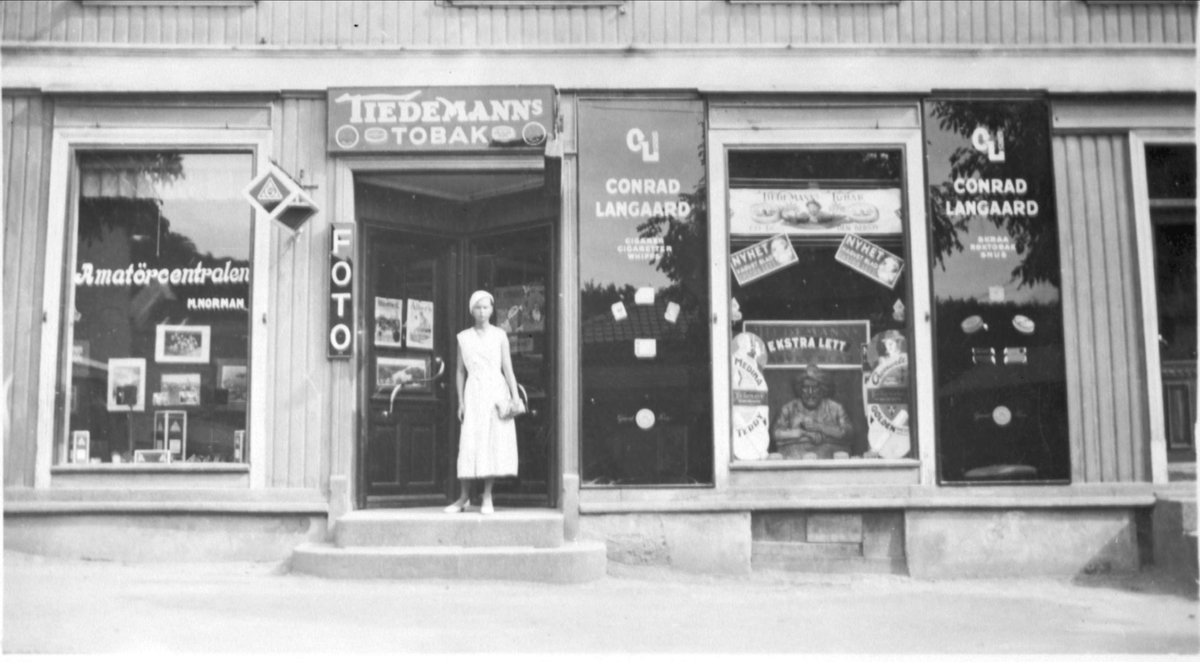 Magdalene Normans fotoforretning "Amatørcentralen", i Larvik. I døråpningen står assistenten hennes (ukjent navn).