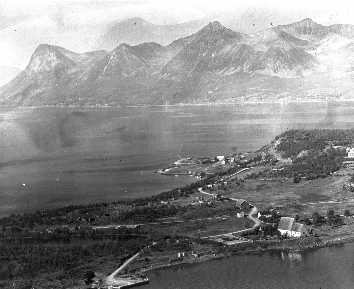 Flyfoto av Trondenes kirke og prestegård, med Grytøya i bakgrunnen.