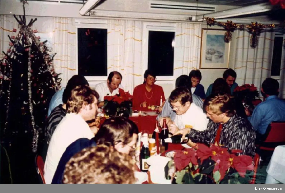 De ansatte spiser middag på Ekofisk 2/4 A, julen 1986. Eli Kulsrud har på rød bluse.