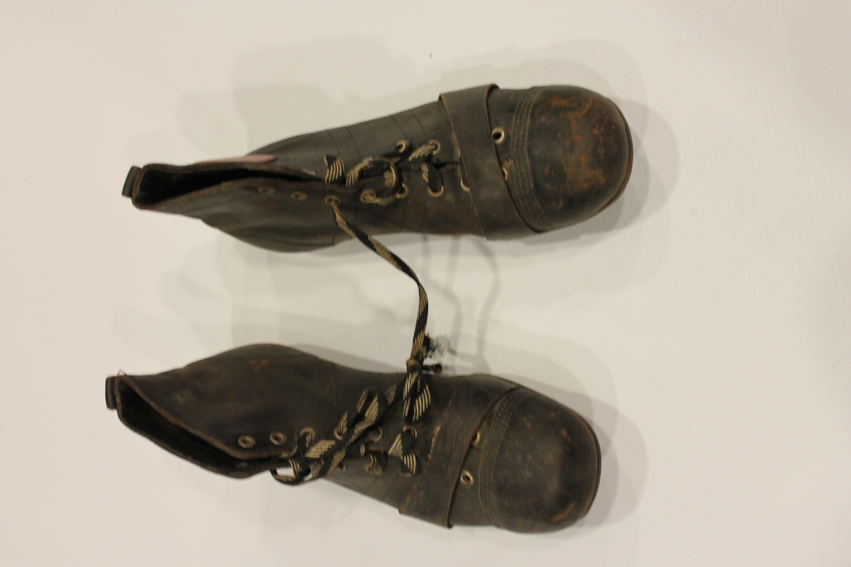 Fotballstøvler med jerntupp, påspikrede knotter og reim. Rødt pyntemerke på siden av begge støvlene. Størrelse 42