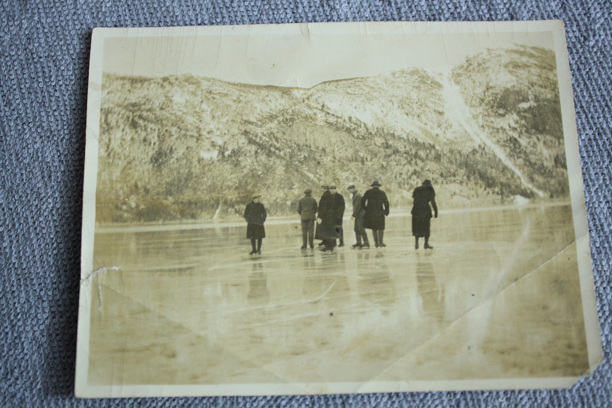 Motiv: Islagt vatn med ei gruppe mennesker på skøyter (7 stk. 1 dame og 6 menn). Klesdraktene tyder på at bilete er tatt i 1930-åra. Låg i bok KSF.011037.