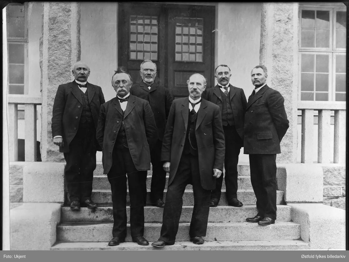 Rakkestad sparebank direksjon på trappa foran banken, 1914. 
Foran fra venstre: H. J. Heier, Ludvig Gjulem. Bak fra venstre: Kristian Edvard Jahren (1865-1937), H. Haaby, Aug.  Gjølstad, J. M. Schie (bankens kasserer i 47 år).