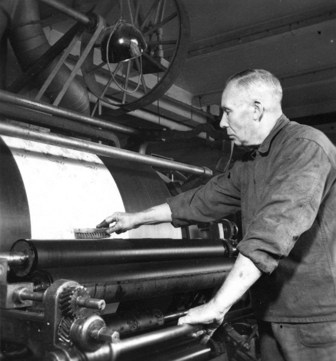 En man arbetar vid tryckmaskinen, mönster "Flocamaskinen" på Papyrus.
Olsson