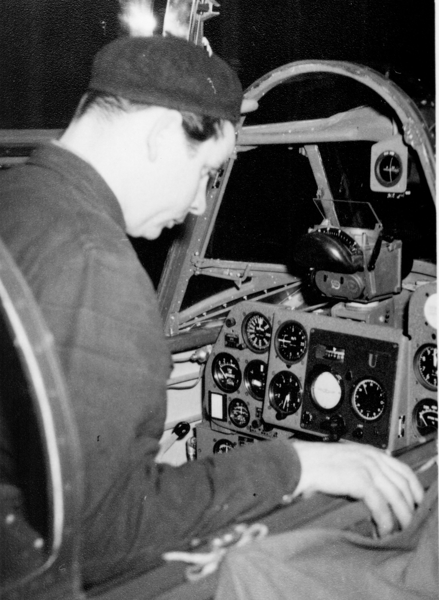 En flygplanstekniker sitter i förarplatsen på flygplan J 21R vid monteringsarbete.