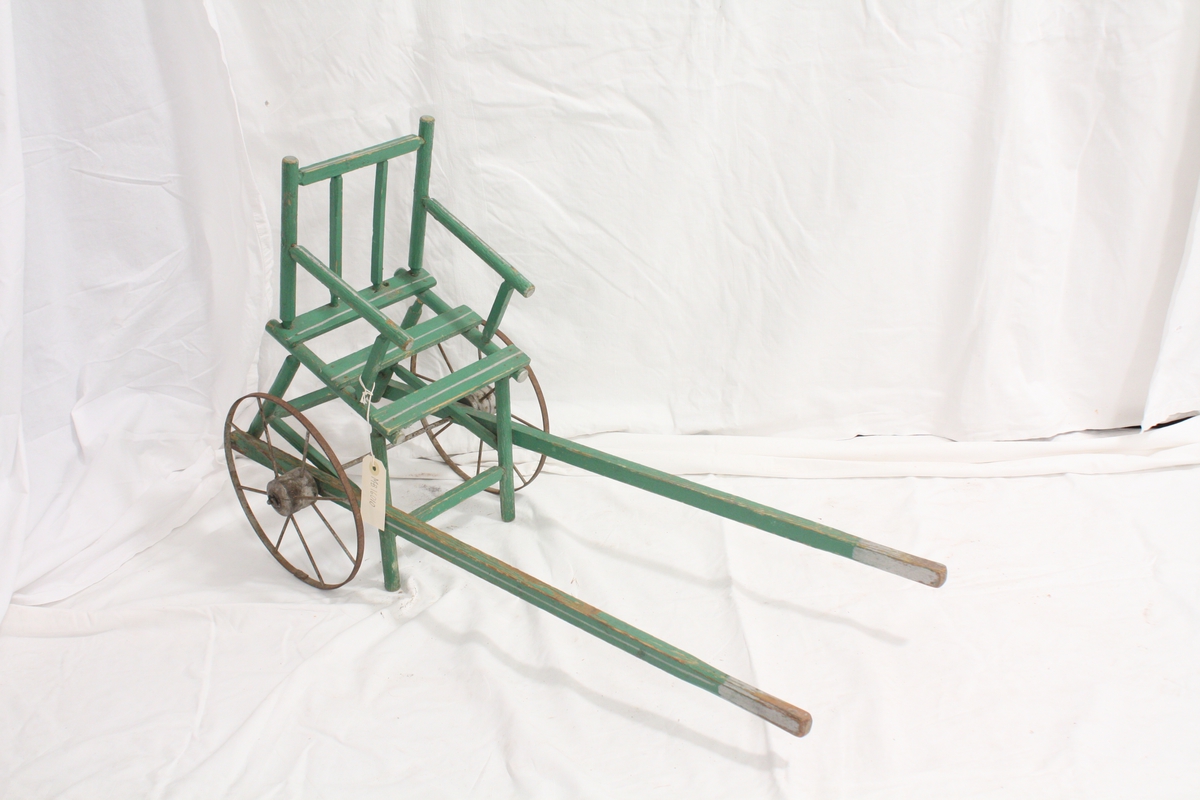Dukkevogn, formet som en stol festet til to kjerrehjul med drag/ to håndtak.