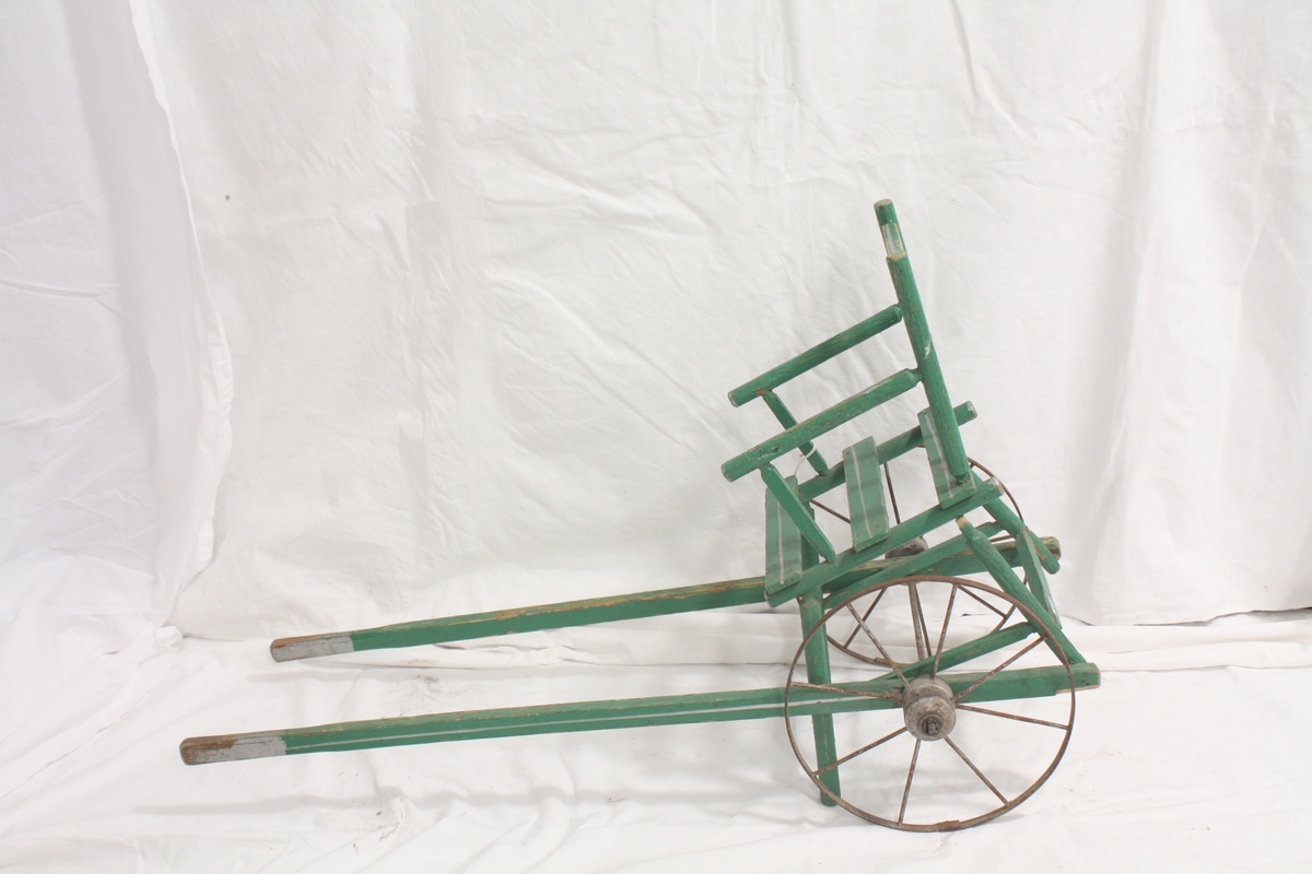 Dukkevogn, formet som en stol festet til to kjerrehjul med drag/ to håndtak.