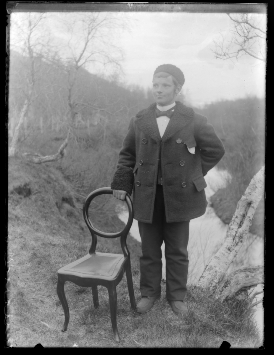 Ung mann stående ute ved en stol