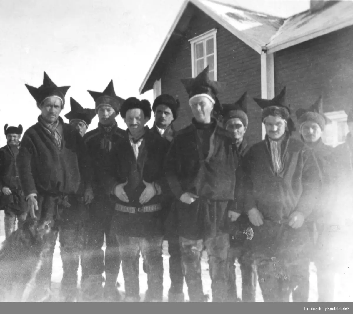 Et gruppebilde fra Utsjoki, Finland. Et gruppe samiske menn står foran et hus. Bildet er et stereobilde.          .