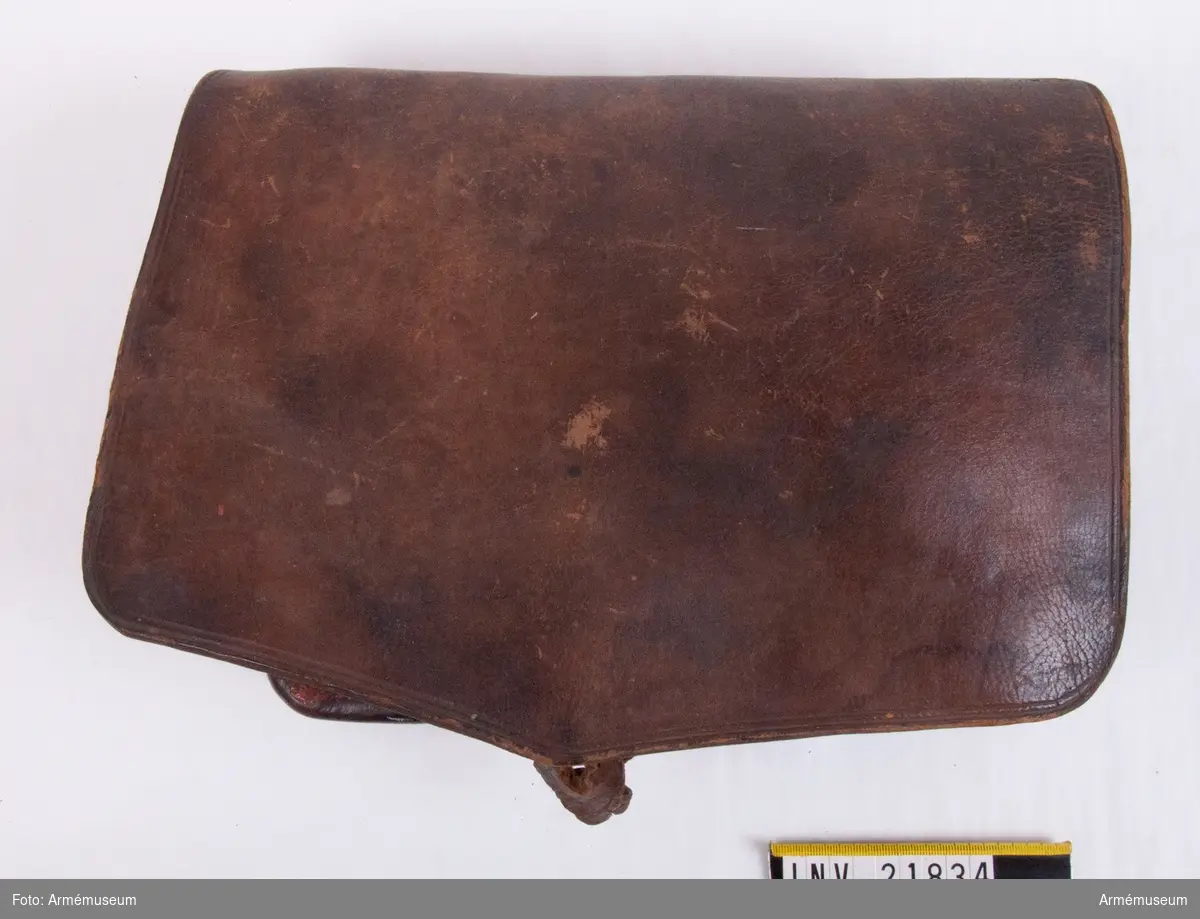 Patronväska av brunt läder med träkloss som insats med plats för 30 patroner. Under locket en ficka för extra flintor.