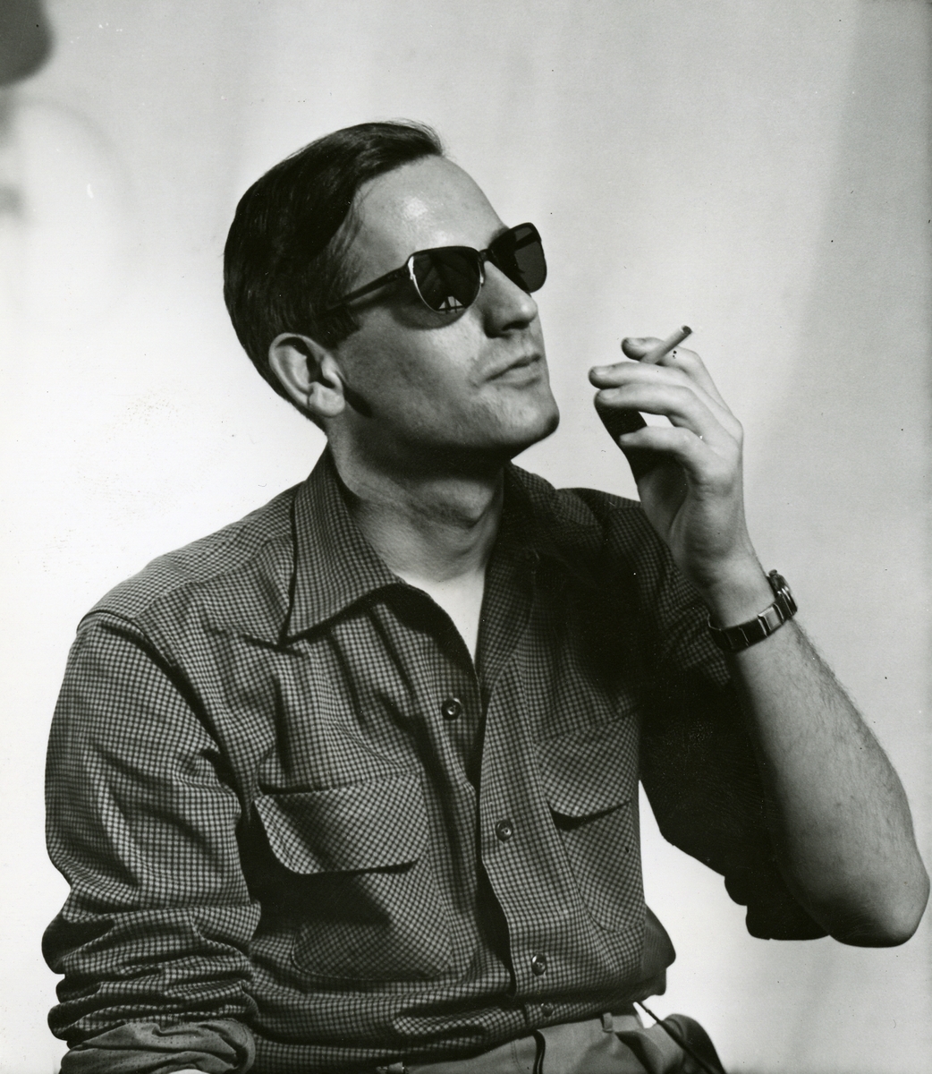 Portrett av mann i solbriller og sigarett i hånden.