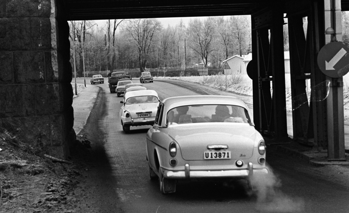 Länsläkaren, Trafiken 24 december 1966

Ett antal bilar och en lastbil kör på en gata. I förgrunden syns en tunnel. Byggnader syns i bakgrunden. Det ligger snö på marken.